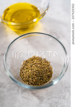 Measured ingredients in glass mixing bowls to make croutons. 107420302