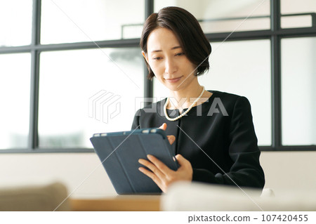 A woman in mourning clothes looking at a tablet A woman in mourning clothes looking at a tablet 107420455