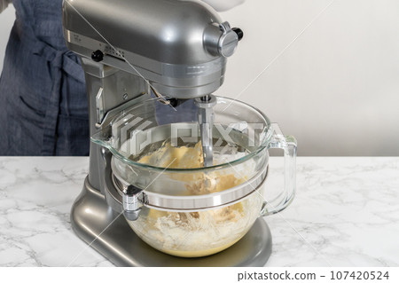 Mixing ingredients in kitchen mixer to bake mini Easter bread kulich. 107420524