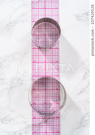 Lemon wedge cookies with lemon glaze. Metal round cookie cutters on a marble kitchen counter. Lemon wedge cookies with lemon glaze. Metal round cookie cutters on a marble kitchen counter. 107420526