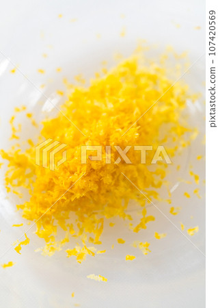 Zesting and juicing fresh lemon on a white cutting board. 107420569