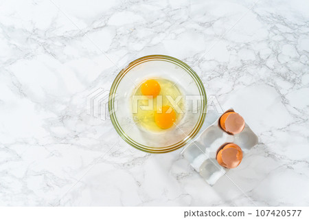 Flat lay. Mixing ingredients in a large glass mixing bowl to bake peppermint white chocolate cookies. 107420577