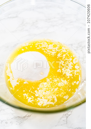 Mixing wet ingredients in a large glass mixing bowl to bake lemon cupcakes. Mixing wet ingredients in a large glass mixing bowl to bake lemon cupcakes. 107420606
