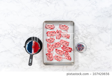 Flat lay. Drizzling melted chocolate over chocolate-dipped pretzels twists. Flat lay. Drizzling melted chocolate over chocolate-dipped pretzels twists. 107420656