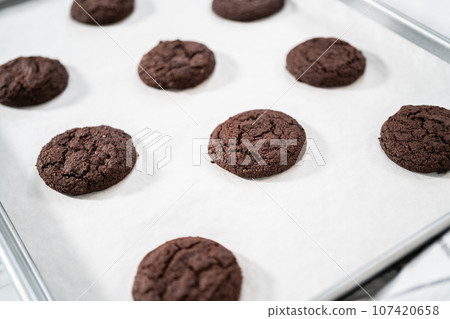 Cooling freshly baked chocolate cookies on a kitchen counter. Cooling freshly baked chocolate cookies on a kitchen counter. 107420658