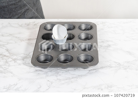 Lining baking cupcake pan with foil liners to bake lemon cupcakes. 107420719