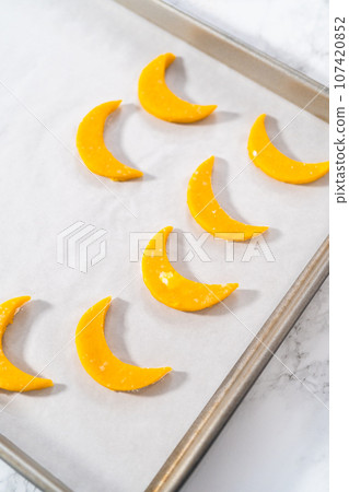 Lemon wedge cookies with lemon glaze. Rolling cookie dough with an adjustable rolling pin and cutting out cookies with cookie cutters to bake lemon wedge cookies with lemon glaze. 107420852