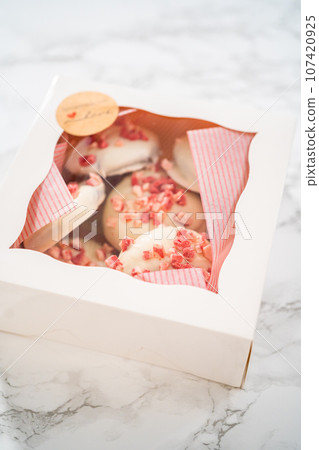 Packing freshly baked peppermint white chocolate cookies into a white paper box. 107420925