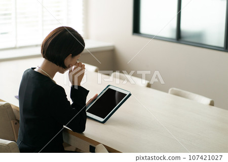 A woman in mourning clothes looking at a tablet device A woman in mourning clothes looking at a tablet device 107421027