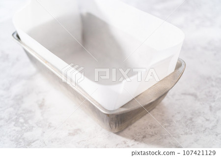 Lining loaf pan with parchment paper to make meatloaf. Lining loaf pan with parchment paper to make meatloaf. 107421129