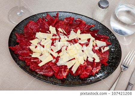 Appetizing raw veal carpaccio served with cheese 107421208