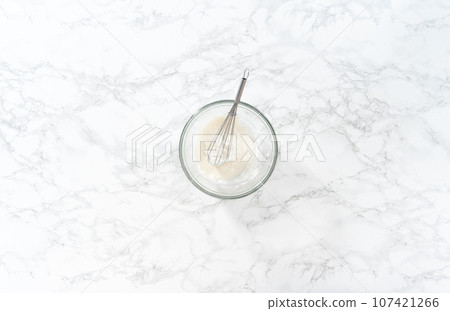Mixing ingredients with a hand mixer in a large mixing bowl to make the lemon glaze for mini Easter bread kulich. Mixing ingredients with a hand mixer in a large mixing bowl to make the lemon glaze for mini Easter bread kulich. 107421266
