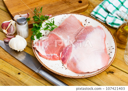Spanish Secreto de cerdo - raw pork cinch with parsley and peppers in plate Spanish Secreto de cerdo - raw pork cinch with parsley and peppers in plate 107421403