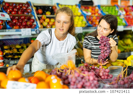 Teenage girl and her mother buying grape at grocery Teenage girl and her mother buying grape at grocery 107421411