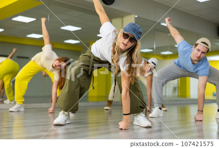 Teenage girl training breakdance drops in dance hall 107421575