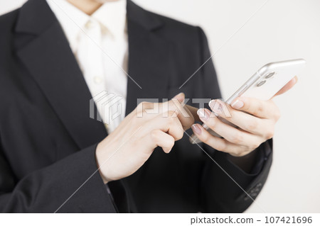 A woman in her 20s wearing a jacket operates a smartphone A woman in her 20s wearing a jacket operates a smartphone 107421696