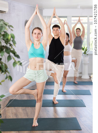 Group of young people doing a tree yoga pose. Group of young people doing a tree yoga pose. 107421786