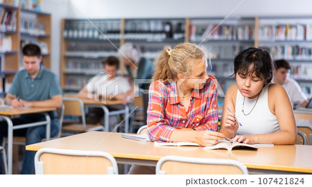 Teaching teenagers in the school library using laptop Teaching teenagers in the school library using laptop 107421824