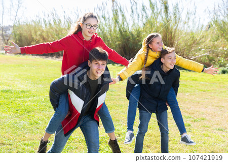 Happy teenage boys piggybacking girls 107421919