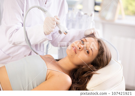 Young woman undergoing skin therapy with application of atomized nutrients 107421921