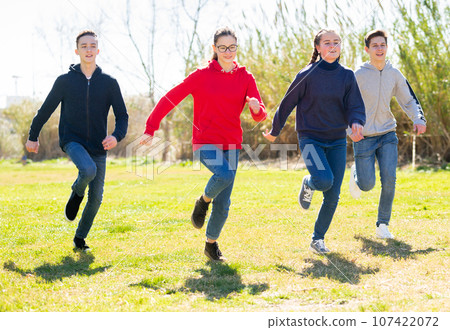 Cheerful teens running on green lawn 107422072