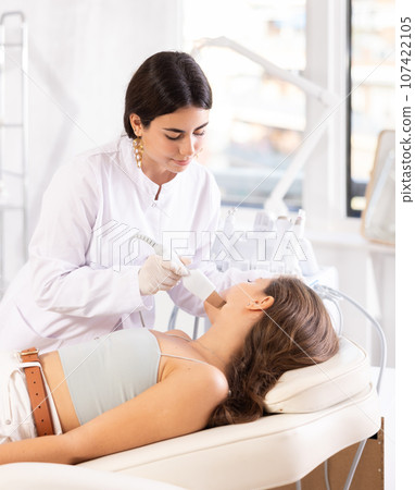 female doctor making facial beauty procedure with leather knife attachment female doctor making facial beauty procedure with leather knife attachment 107422105