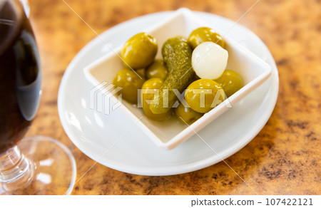 Marinated green olives, gherkins and pearl onions on plate 107422121
