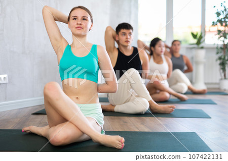 Young teen lady performs cow head pose, Gomukhasana 107422131