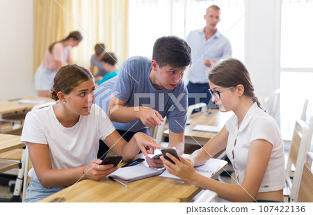 Classmates and teacher working in groups to complete task during class Classmates and teacher working in groups to complete task during class 107422136