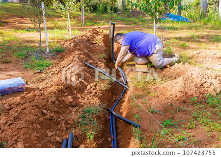 Plumber uses thermal insulation PE foam to cover underground PVC water pipes Plumber uses thermal insulation PE foam to cover underground PVC water pipes 107423755