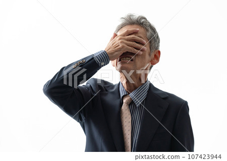 An elderly businessman holding his face and crying An elderly businessman holding his face and crying 107423944