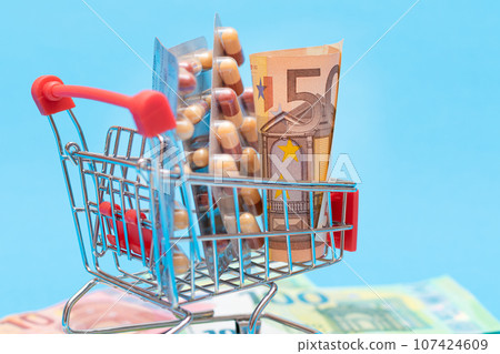 Pills and Capsules in Shopping Cart on Blue Background 107424609