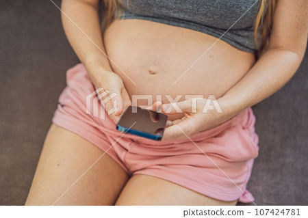 Mobile pregnancy online maternity application. Pregnant mother using phone. Pregnancy, medicine, pharmaceutics, health care and people concept Mobile pregnancy online maternity application. Pregnant mother using phone. Pregnancy, medicine, pharmaceutics, health care and people concept 107424781