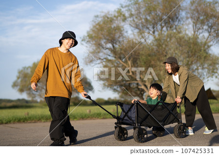 Image of a family pulling a child on a camping/outdoor cart Image of a family pulling a child on a camping/outdoor cart 107425331