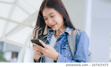 Young asian woman smiling using mobile smart phone outdoor 107425473