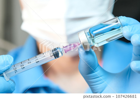 doctor's hand holds a syringe and a blue vaccine bottle at the hospital. Health and medical concepts. doctor's hand holds a syringe and a blue vaccine bottle at the hospital. Health and medical concepts. 107426681
