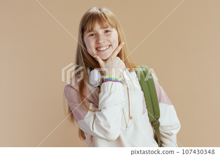 Portrait of smiling modern school girl in beige tracksuit 107430348