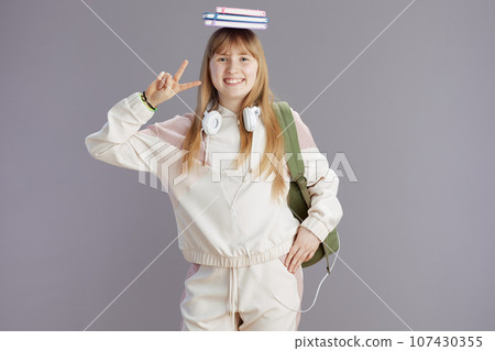 smiling school girl in beige tracksuit showing victory smiling school girl in beige tracksuit showing victory 107430355