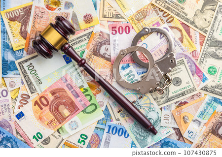 Judge gavel, handcuffs on various banknotes background. 107430875