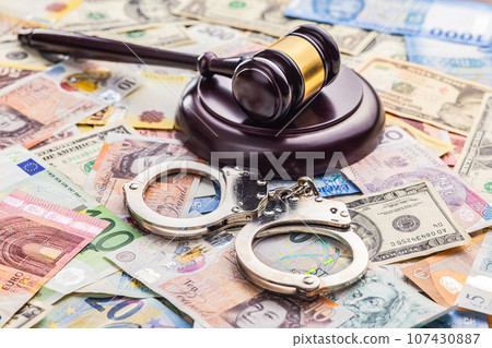 Judge gavel and  handcuffs on various banknotes background. 107430887