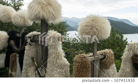 Georgian papakhas are sold to tourists against the backdrop of mountains. Journey along the military Georgian road. Georgian papakhas are sold to tourists against the backdrop of mountains. Journey along the military Georgian road. 107431910
