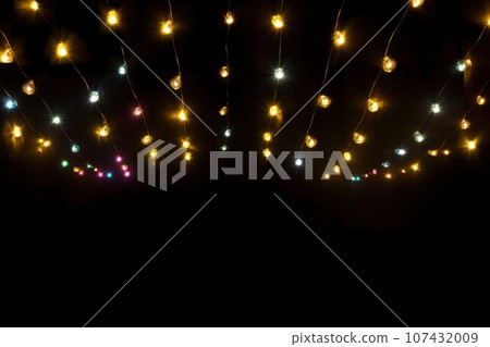 Gold Twinkle Christmas string lights on black background. Defocused Glowing light bulb garland. Generative AI 107432009