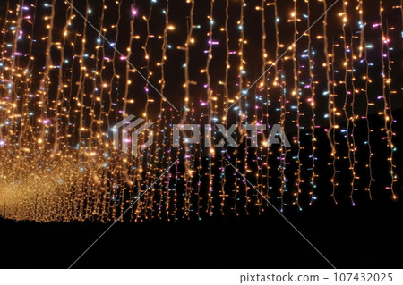 Gold Twinkle Christmas string lights on black background. Defocused Glowing light bulb garland. Generative AI 107432025
