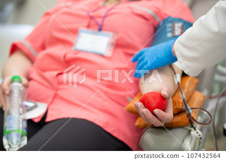 Close-up of a woman's hand squeezing a ball out of stress while donating blood at a blood donation center. 107432564