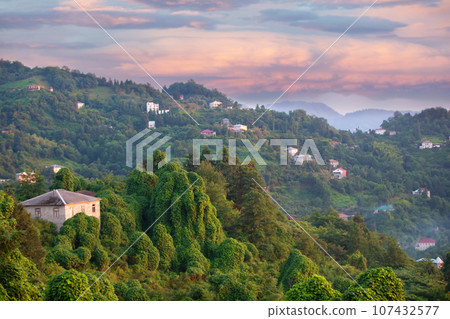 Beautiful tourist landscape of a mountainous area with a small house and a colorful sky. Mountains of Georgia. 107432577