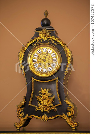 Vintage wooden table clock with nineteenth century gold details. Vintage wooden table clock with nineteenth century gold details. 107432578