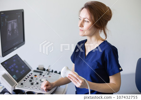 Doctor woman doing ultrasound scanning diagnostic of thyroid gland sitting in office in clinic. 107432755
