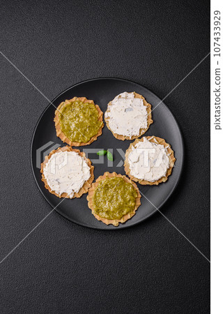 Round snacks with crispy chips or crackers with cream cheese and pesto 107433929