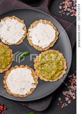 Round snacks with crispy chips or crackers with cream cheese and pesto 107433934