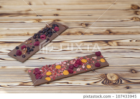 different kinds of chocolate with dried fruits on a wooden board different kinds of chocolate with dried fruits on a wooden board 107433945